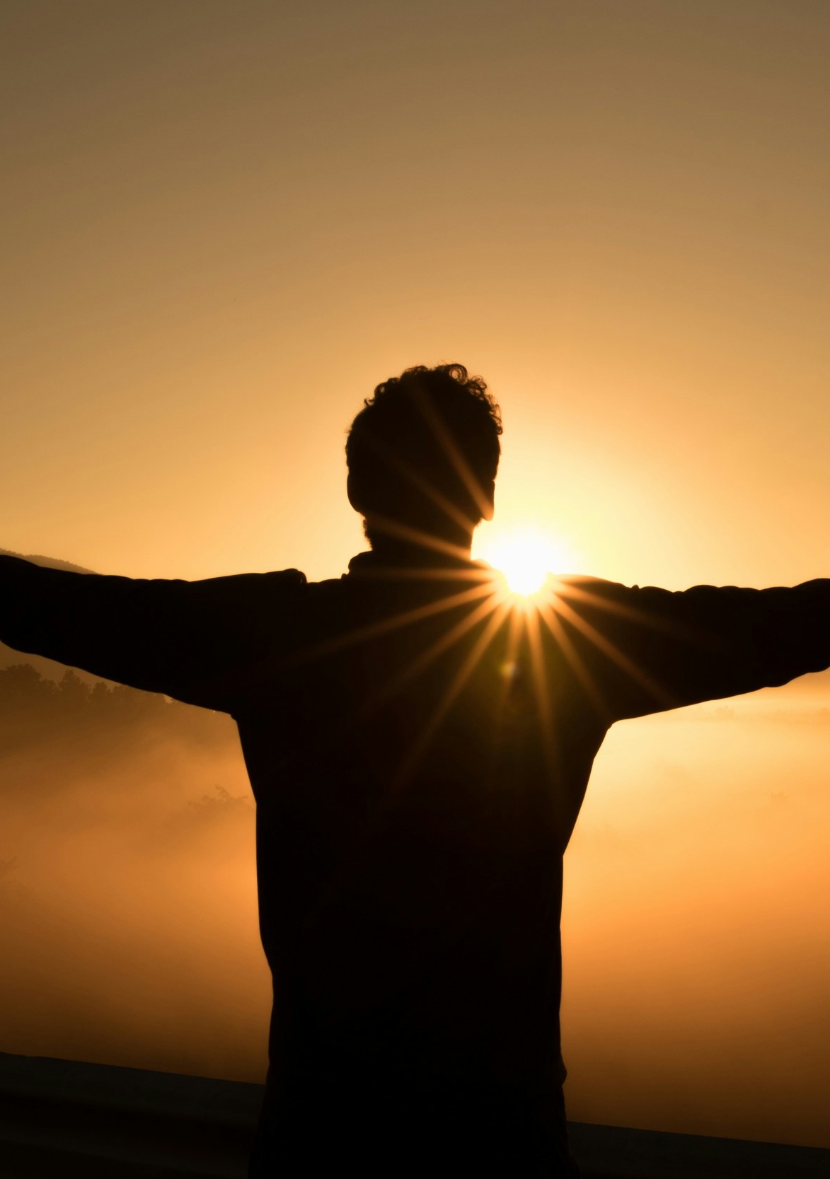 Man stretching looking at a sunrise